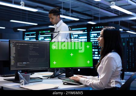 Developer coworkers using mockup laptop to check server clusters configuration settings. Specialists checking event logs in monitoring software on chroma key notebook in data center Stock Photo