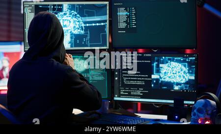 Evil cybercriminal using AI deep learning to produce virus corrupting data. Rogue programmer working on PC using artificial intelligence technology, penetrating security systems, camera A Stock Photo