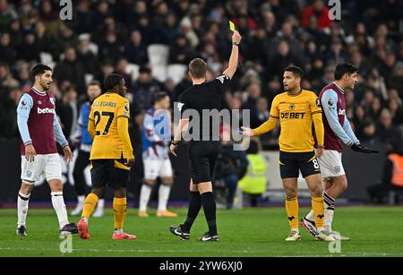 London, UK. 9th Dec, 2024. John Brooks (Referee) shows the yellow card to João Gomes (Wolves, 8) during the West Ham vs Wolverhampton Wanderers Premier League match at the London Stadium Stratford. This Image is for EDITORIAL USE ONLY. Licence required from the Football DataCo for any other use. Credit: MARTIN DALTON/Alamy Live News Stock Photo