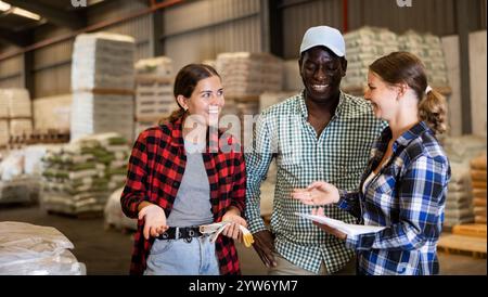 Workers and manager discussing completed work in large warehouse Stock Photo