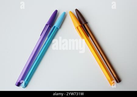 Colorful ballpoint pens arranged in triangular shape on white background. Cool and warm colors. Creative stationery, school supplies, education theme. Stock Photo