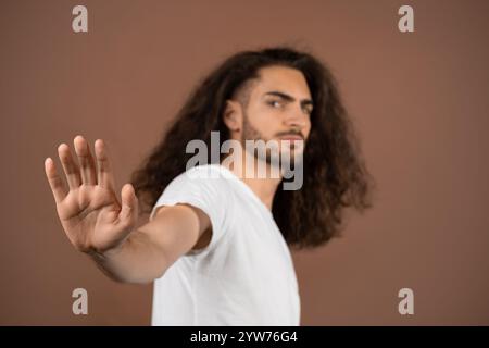 Curly-haired young man confidently poses in casual outfit Stock Photo