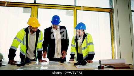 Architecture, pointing and blueprint with people on construction site for building, real estate and inspection. Engineer, planning and property Stock Photo