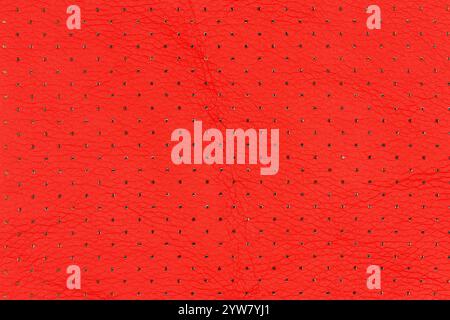 Bright red color abstract artificial leather with small dots and holes pattern for background. Close-up view of vibrant red breathable surface Stock Photo