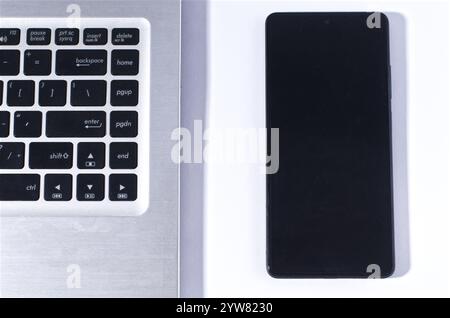 Modern Technology Concept Featuring a Smartphone and Laptop Keyboard on White Background Stock Photo