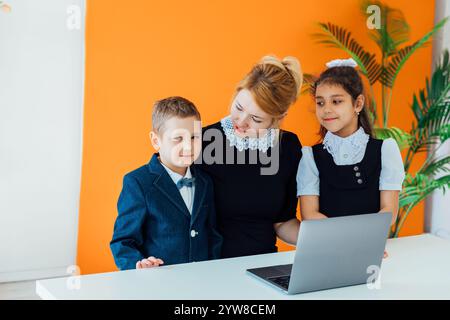 Teacher and boy with girl schoolchildren with laptop Stock Photo