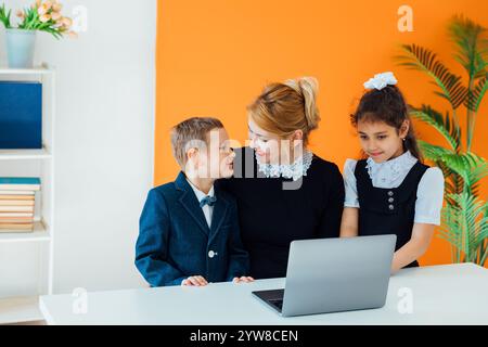 Teacher and boy with girl schoolchildren with laptop Stock Photo
