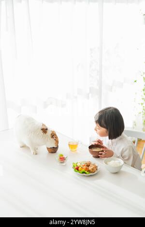 Girl and cat eating breakfast Stock Photo