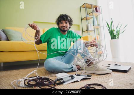 Full length portrait of nice young man hold tied internet cable wi-fi router wear t-shirt modern green interior flat indoors Stock Photo