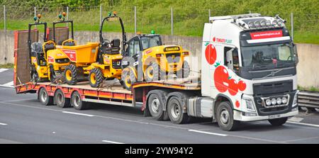 Haulage contractor hgv lorry truck articulated low loader semi trailer carrying heavy building construction equipment driving M25 motorway England UK Stock Photo