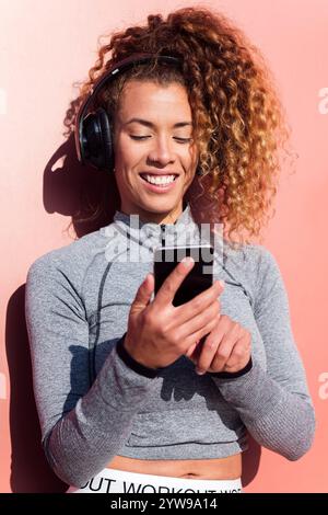 latin woman in headphones using mobile phone Stock Photo