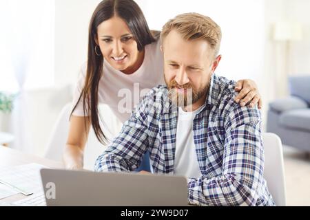 Happy married couple using laptop, managing family budget, paying taxes and house bills Stock Photo