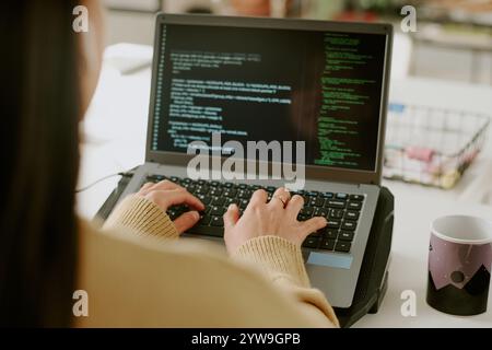 Back view of unrecognizable woman typing on laptops keyboard to write codes in cozy office Stock Photo