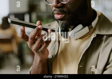 Medium close up of unrecognizable African American man with headphones around neck recording voice message Stock Photo