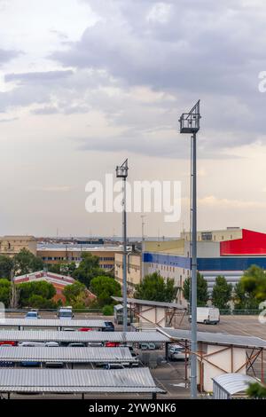 Vehicle parking with metal fences and lighting towers on an industrial site Stock Photo