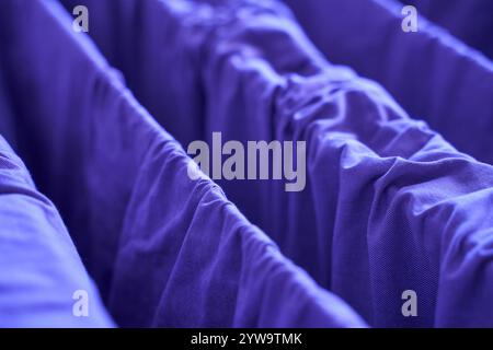 Blue fabric curtains close up showing texture and folds in a dimly lit setting. Stock Photo