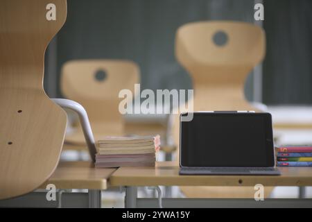 School furniture with a black tablet and textbooks in an empty classroom. Bavaria, Germany, Europe Stock Photo