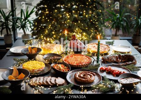 Festive table setting with Christmas decorations and burning candles in the dining room, cozy romantic Christmas in the evening atmosphere Stock Photo