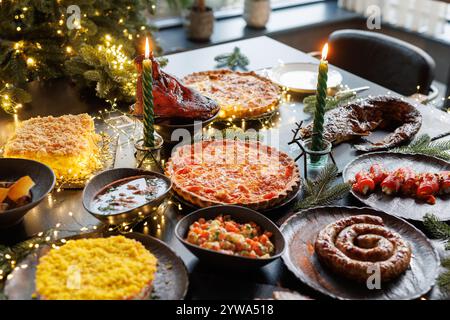 Festive table setting with Christmas decorations and burning candles in the dining room, cozy romantic Christmas in the evening atmosphere Stock Photo