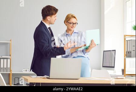 Business accountant and her colleague looking at a document on a laptop computer Stock Photo