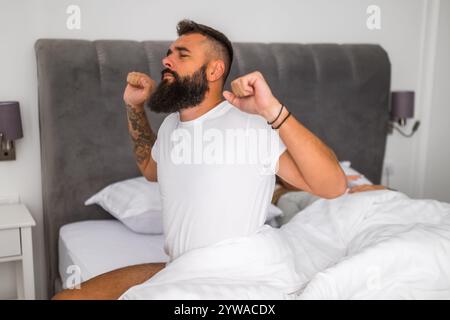 Young couple is sleeping in bed. Man is waking up for work. Stock Photo
