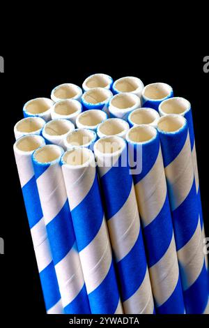 A bundle of blue and white, paper drinking straws, photographed against a black background Stock Photo