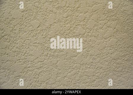 A wall with a textured surface. The wall is tan in color. The texture is rough and bumpy Stock Photo
