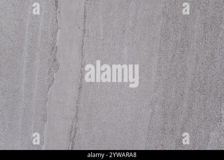 A grey stone wall with a crack in it. The crack is about the size of a quarter Stock Photo