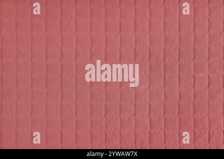 Checkered stitching pattern, red quilted fabric background. Blanket or puffer jacket, stitch square texture close up, macro. Wallpaper, backdrop. Stock Photo