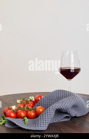 A Beautifully Arranged Red Wine Glass along with Fresh Cherry Tomatoes on a Dark Wooden Table Stock Photo
