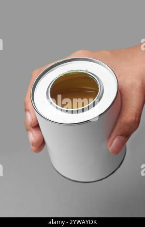 hand holding yellow adhesive in silver tin can isolated gray background, mock-up template of synthetic glue metal container with blank label Stock Photo