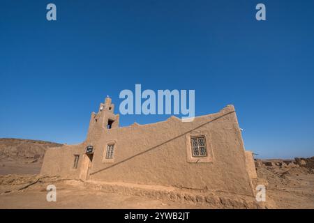 A mosque made of adobe bricks and mud in the sun of the Moroccan desert near Merzouga. You can see the minaret and the small windows with typical deco Stock Photo