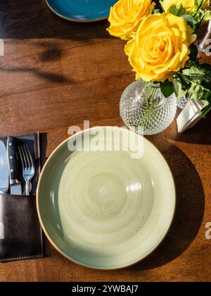 above view of empty green ceramic bowl and yellow roses on brown table Stock Photo