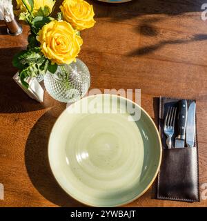 fresh yellow roses and empty green ceramic plate on brown table Stock Photo