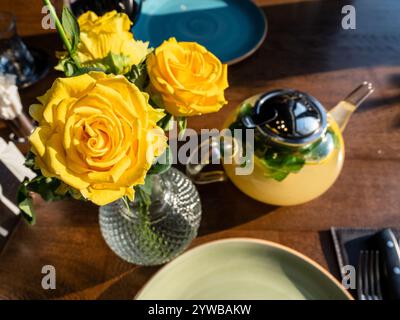 fresh yellow roses on served table with glass teapot Stock Photo