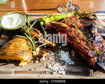 cut medium rare grilled t-bone beef steak closeup on wooden cutting board with potato Stock Photo