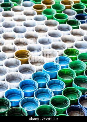 many used empty plastic bottle caps laid out on surface Stock Photo