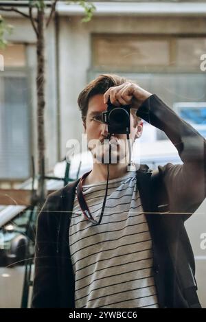 Photographer taking a selfie in the reflection of a storefront window Stock Photo