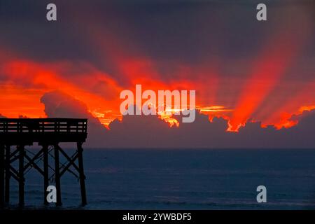 Isle Of Palms, United States. 10th Dec, 2024. Dawn breaks behind heavy clouds as a front pushes through the low country causing crepuscular rays to radiate outwards as the sun rises over the Atlantic Ocean along Front Beach, December 10, 2024 in Isle of Palms, South Carolina. The warm and humid weather will give way to a cold front later in the week. Credit: Richard Ellis/Richard Ellis/Alamy Live News Stock Photo