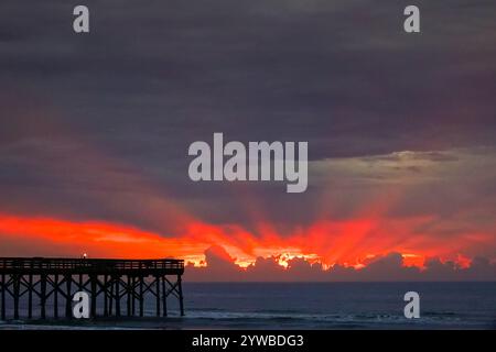 Isle Of Palms, United States. 10th Dec, 2024. Dawn breaks behind heavy clouds as a front pushes through the low country causing crepuscular rays to radiate outwards as the sun rises over the Atlantic Ocean along Front Beach, December 10, 2024 in Isle of Palms, South Carolina. The warm and humid weather will give way to a cold front later in the week. Credit: Richard Ellis/Richard Ellis/Alamy Live News Stock Photo