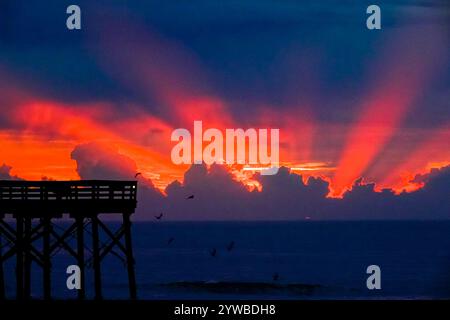 Isle Of Palms, United States. 10th Dec, 2024. Dawn breaks behind heavy clouds as a front pushes through the low country causing crepuscular rays to radiate outwards as the sun rises over the Atlantic Ocean along Front Beach, December 10, 2024 in Isle of Palms, South Carolina. The warm and humid weather will give way to a cold front later in the week. Credit: Richard Ellis/Richard Ellis/Alamy Live News Stock Photo