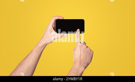 Unrecognizable millennial man touching screen of cellphone over light background, space for mobile app design Stock Photo