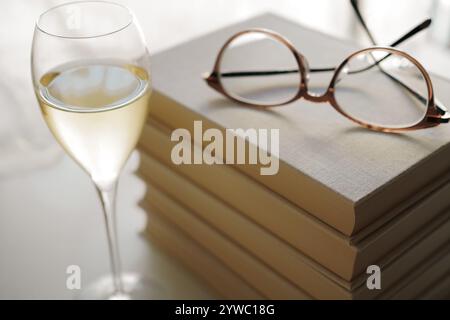 Glasses on top of a stack of books and a glass of white wine Stock Photo