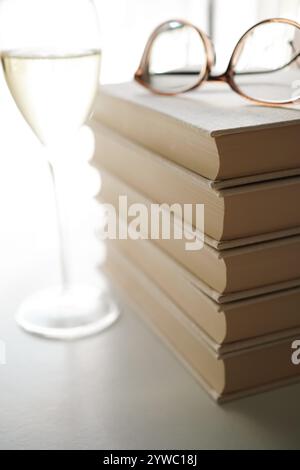 Glasses on top of a stack of books and a glass of white wine Stock Photo