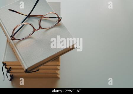 A pair of glasses and a pile of books on a white background Stock Photo
