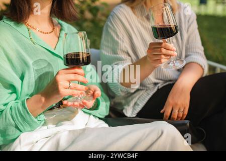 Close-up of two women sitting on a terrace drinking red wine in summer Stock Photo