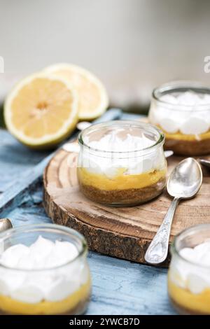 Close-up of individual servings of lemon meringue pies on a wooden chopping board with fresh lemons Stock Photo