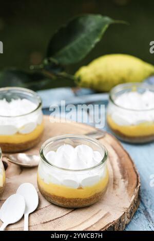 Close-up of individual servings of lemon meringue pies on a wooden chopping board with fresh lemons Stock Photo