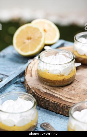 Close-up of individual servings of lemon meringue pies on a wooden chopping board with fresh lemons Stock Photo