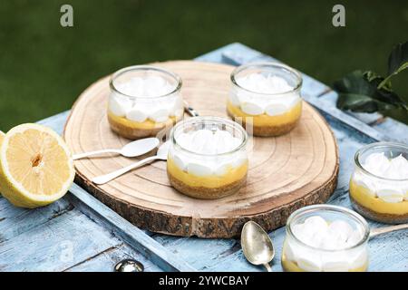 Close-up of individual servings of lemon meringue pies on a wooden chopping board with fresh lemons Stock Photo